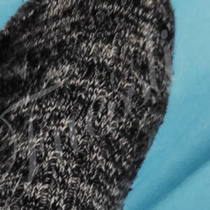 Füße in grauen Wollsocken im Bett.